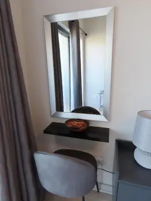 a mirror on a wall with a chair in a room at Cape Town Luxury Stays Knightsbridge Luxury Apartment Century City in Cape Town
