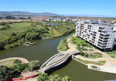 a bridge over a river next to a building at Cape Town Luxury Stays Knightsbridge Luxury Apartment Century City in Cape Town