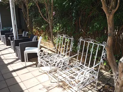 a group of white chairs sitting on a patio at Rusticana Room1 in Cape Town