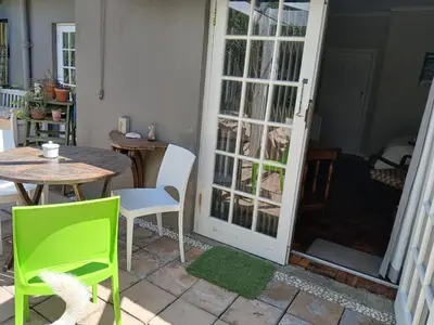 a room with a table and chairs and a door at Rusticana Room1 in Cape Town