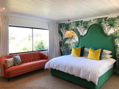 a bedroom with a large bed and a red couch at Best of Both! Mountain and Sea View Home. in Hermanus