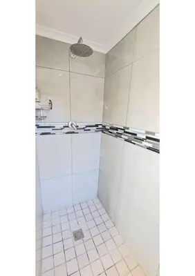 a bathroom with white tiled floors and a shower at Heart of Obz in Cape Town