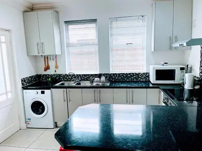 a kitchen with white cabinets and a black counter top at Heart of Obz in Cape Town