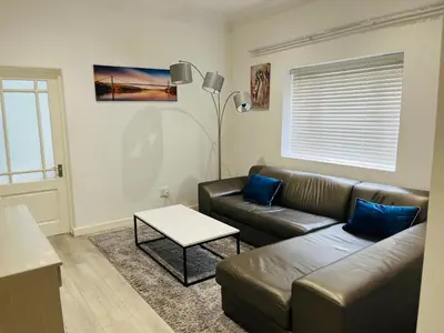 a living room with a leather couch and a table at Heart of Obz in Cape Town
