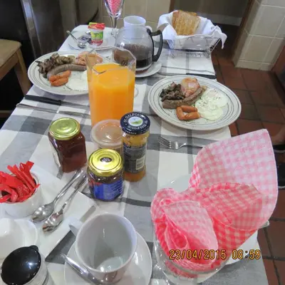 a table topped with plates of breakfast food and orange juice at Guesthouse De Tijger Lodge in Parow