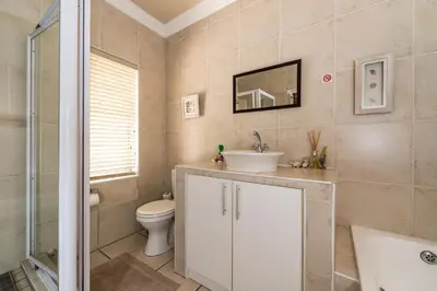 a bathroom with a sink and a toilet and a mirror at Guesthouse De Tijger Lodge in Parow
