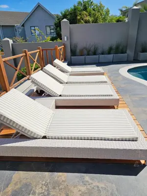a row of white beds sitting next to a pool at Casa La Vista in Somerset West