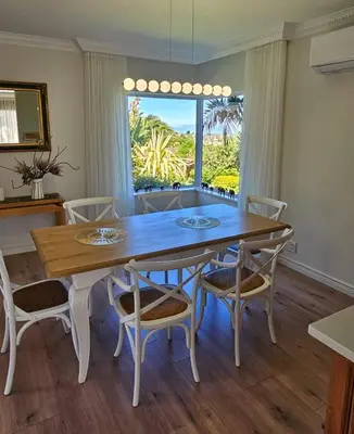 a dining room with a table and chairs and a window at Casa La Vista in Somerset West