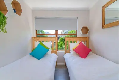 two beds in a room with a window at Beachfront Bliss at Malgas Views in Gordonʼs Bay