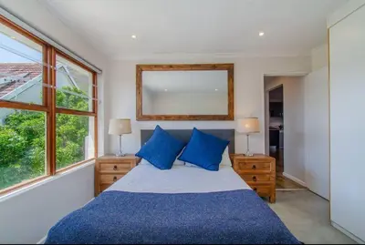 a bedroom with a bed with blue pillows and a mirror at Beachfront Bliss at Malgas Views in Gordonʼs Bay