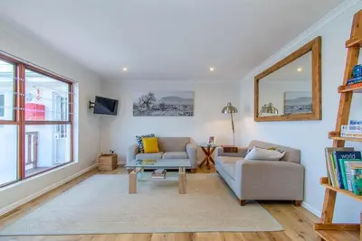 a living room with a couch and a table at Beachfront Bliss at Malgas Views in Gordonʼs Bay