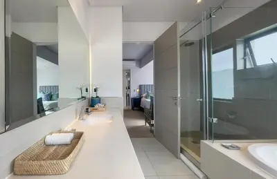a bathroom with a walk in shower and a sink at Le Paradis Penthouse in Hermanus
