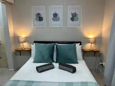 a bedroom with a bed with two pillows and two lamps at Addai Self Catering Brackenfell Durbanville area in Cape Town