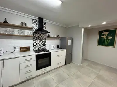a kitchen with white cabinets and a stove top oven at Addai Self Catering Brackenfell Durbanville area in Cape Town