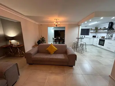 a living room with a couch and a kitchen at Addai Self Catering Brackenfell Durbanville area in Cape Town
