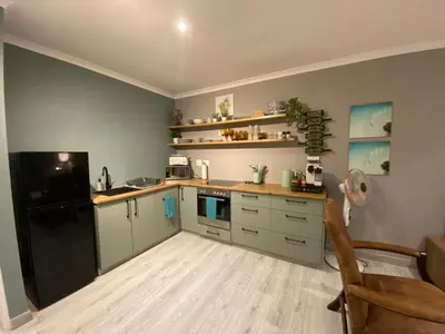 a kitchen with green cabinets and a black refrigerator at Marble Maison in Franschhoek