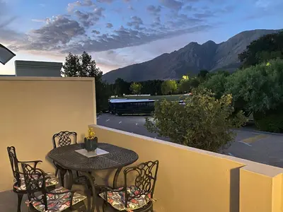 a patio table and chairs on a balcony with mountains at Marble Maison in Franschhoek