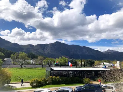 a building with cars parked in a parking lot with mountains at Marble Maison in Franschhoek