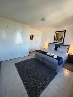 a bedroom with a large bed and a black rug at Stay with me in Cape Town