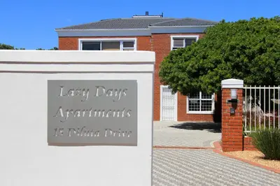 a sign on a white fence in front of a house at Lazy Days Apartments - Cape Town in Cape Town