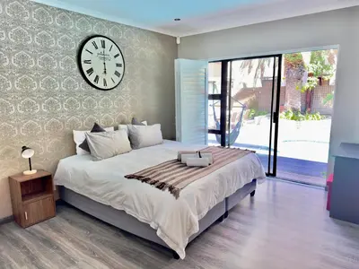 a bedroom with a large bed with a clock on the wall at The Kite Villa - Luxury Kitesurfing Guesthouse in Cape Town