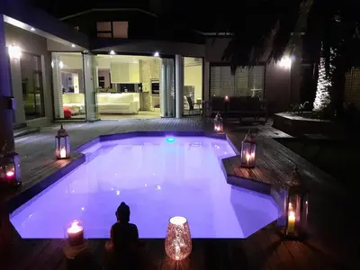 a swimming pool at night with lights and candles at The Kite Villa - Luxury Kitesurfing Guesthouse in Cape Town