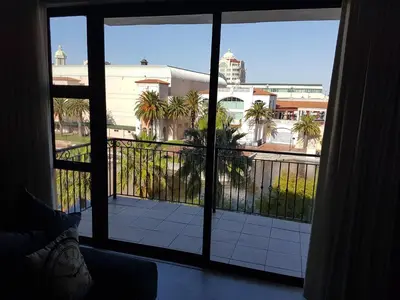 a room with a view of a balcony with palm trees at The Island Club Apartment in Cape Town