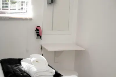 a white room with a black couch and a phone at Panthera Cottage Milnerton in Cape Town