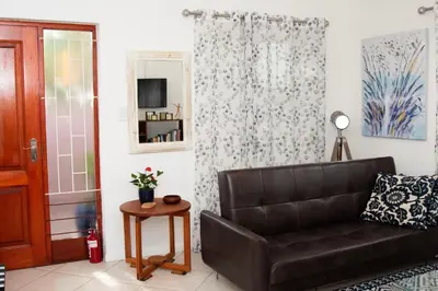 a living room with a leather couch and a mirror at Panthera Cottage Milnerton in Cape Town
