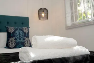 a stack of towels sitting on top of a bed at Panthera Cottage Milnerton in Cape Town