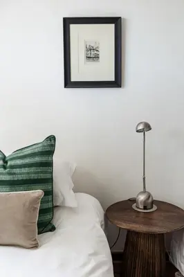 a bed with a green pillow and a table at Silvertree Collective Central Family Home in Stellenbosch