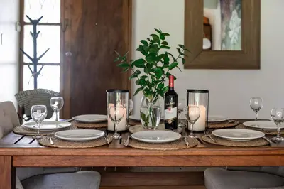 a dining room table with a bottle of wine and glasses at Silvertree Collective Central Family Home in Stellenbosch