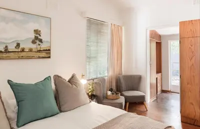 a bedroom with a bed and a chair and a window at Silvertree Collective Central Family Home in Stellenbosch