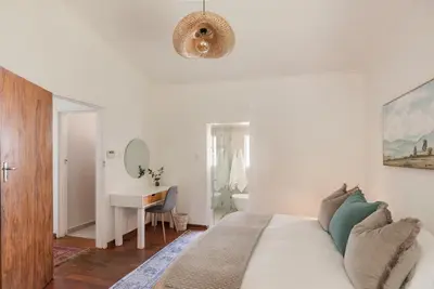 a white bedroom with a bed and a desk at Silvertree Collective Central Family Home in Stellenbosch