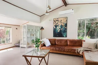 a living room with a brown leather couch at Silvertree Collective Central Family Home in Stellenbosch