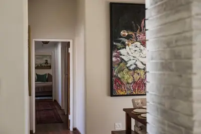 a hallway with a painting hanging on a wall at Silvertree Collective Central Family Home in Stellenbosch