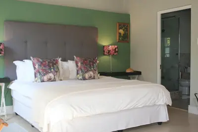a bedroom with a large white bed with green walls at The Cottage on 55 in Franschhoek