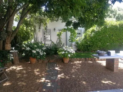 a garden with a table and flowers in front of a house at The Cottage on 55 in Franschhoek