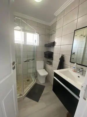 a bathroom with a shower and a toilet and a sink at 42 Whale Rock Estate in Hermanus