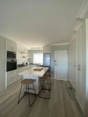 a kitchen with a white island and stools at 42 Whale Rock Estate in Hermanus