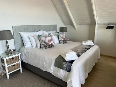 a bedroom with a large bed with pillows at Tranquility Betty's Bay in Sunny Seas