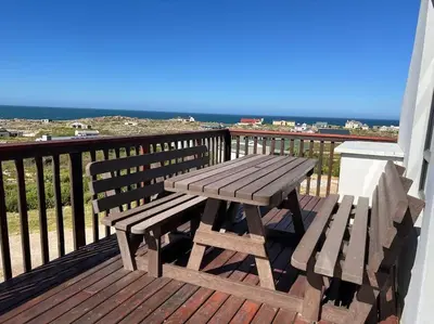 a wooden picnic table and bench on a balcony at Tranquility Betty's Bay in Sunny Seas
