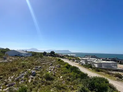 a dirt road on a hill with buildings and the ocean at Tranquility Betty's Bay in Sunny Seas