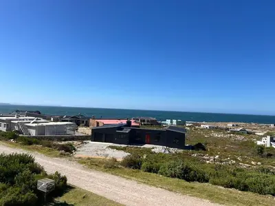 a building on a hill next to a dirt road at Tranquility Betty's Bay in Sunny Seas