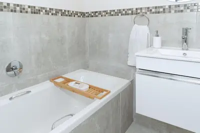 a bathroom with a white tub and a sink at Blouberg Coastal Hideout, Luxury Apartment with a Braai and Parking in Cape Town