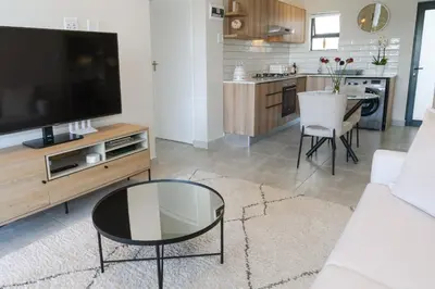a living room with a large television and a table at Blouberg Coastal Hideout, Luxury Apartment with a Braai and Parking in Cape Town