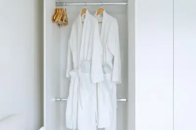 a wardrobe with white robes and shoes at Blouberg Coastal Hideout, Luxury Apartment with a Braai and Parking in Cape Town