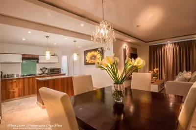 a dining room table with yellow flowers in a vase at Sunset Beach Luxury Apartments in Cape Town