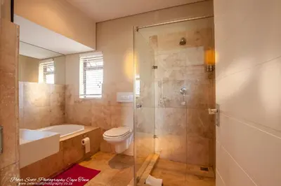 a bathroom with a shower and a toilet and a sink at Sunset Beach Luxury Apartments in Cape Town