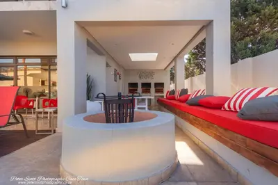 a living room with a red couch and a table at Sunset Beach Luxury Apartments in Cape Town